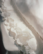 Close-up of layered scalloped ruffles and airy gauze detailing on the Crème duvet cover