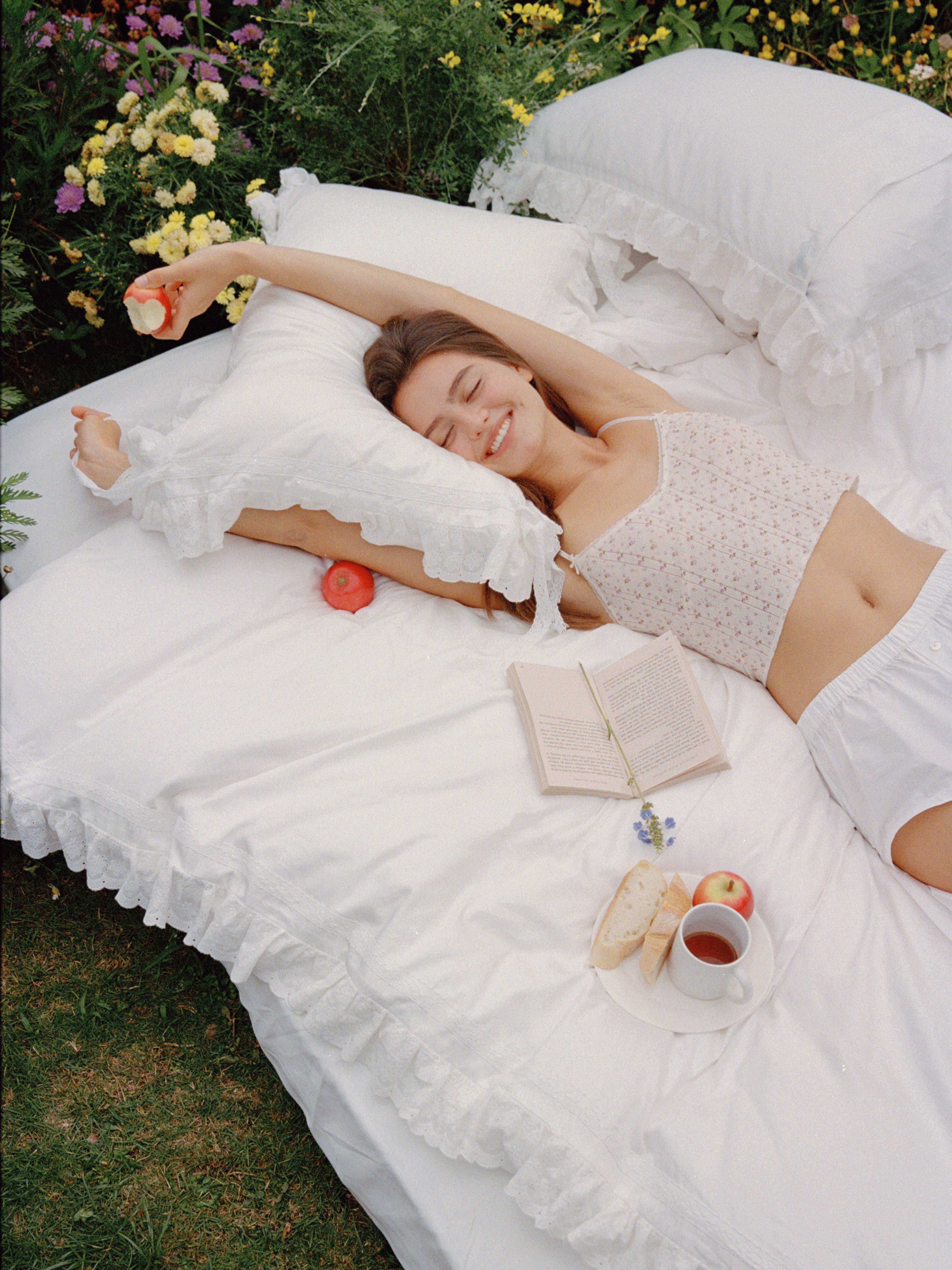 Woman relaxing on the Chantilly ruffle and bow bedding set outdoors