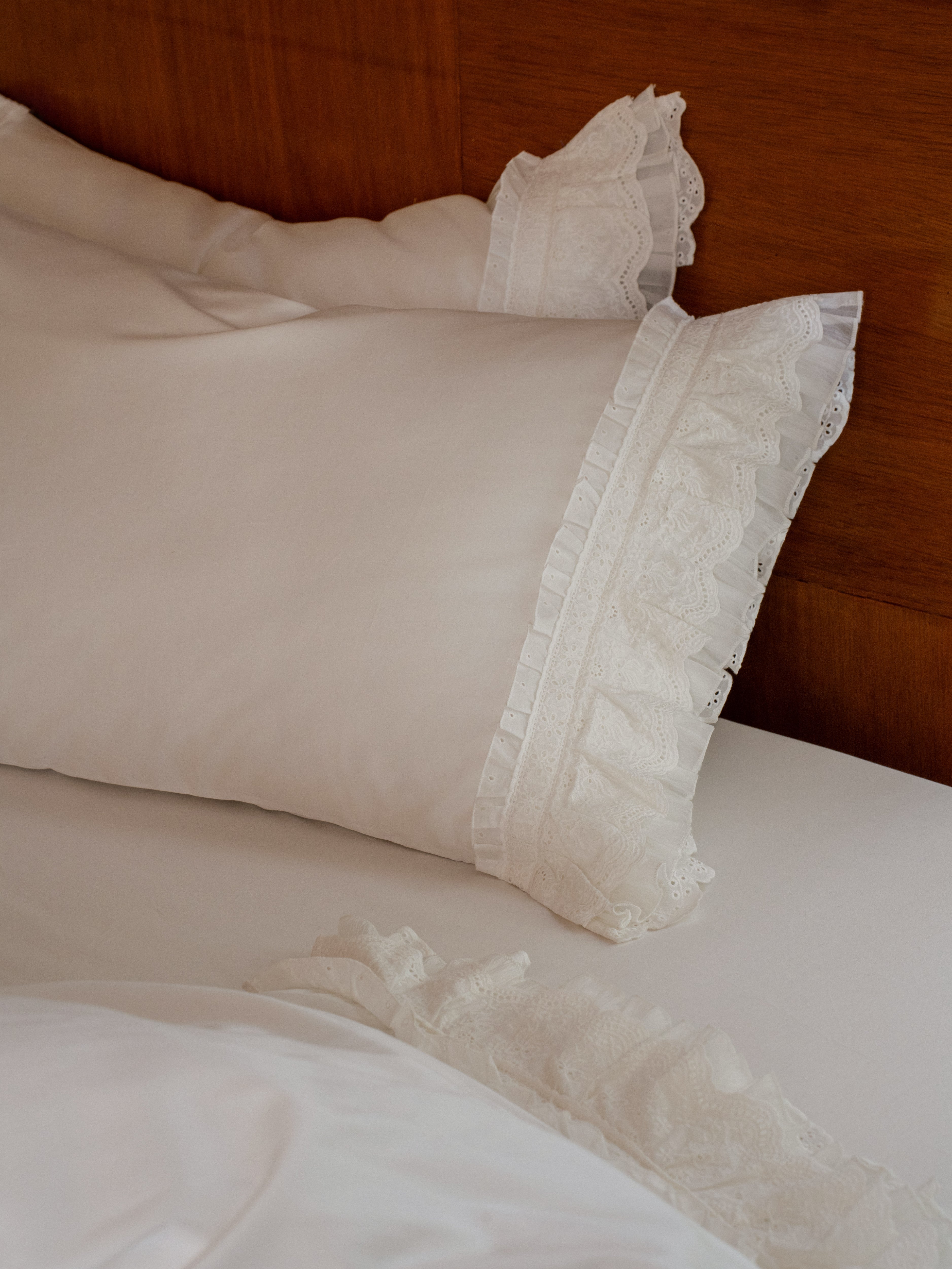 Crème layered ruffle pillowcases in ivory Egyptian cotton sateen styled on a bed
