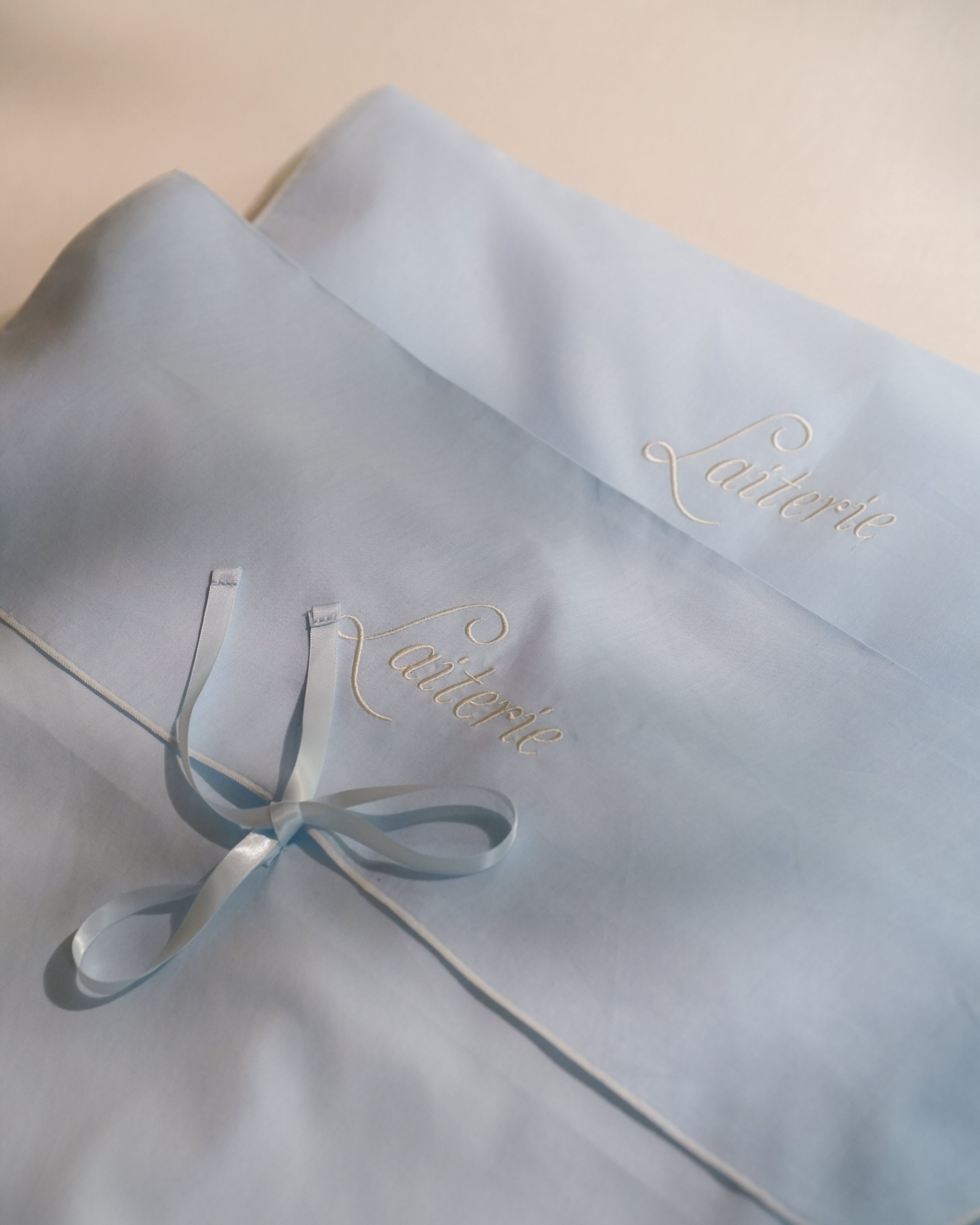 Dusty blue Laiterie Keepsake Bag with embroidered logo and ribbon bow closure