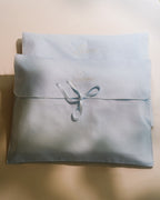 Laiterie cotton muslin keepsake bags in dusty blue with embroidered logo and ribbon tie