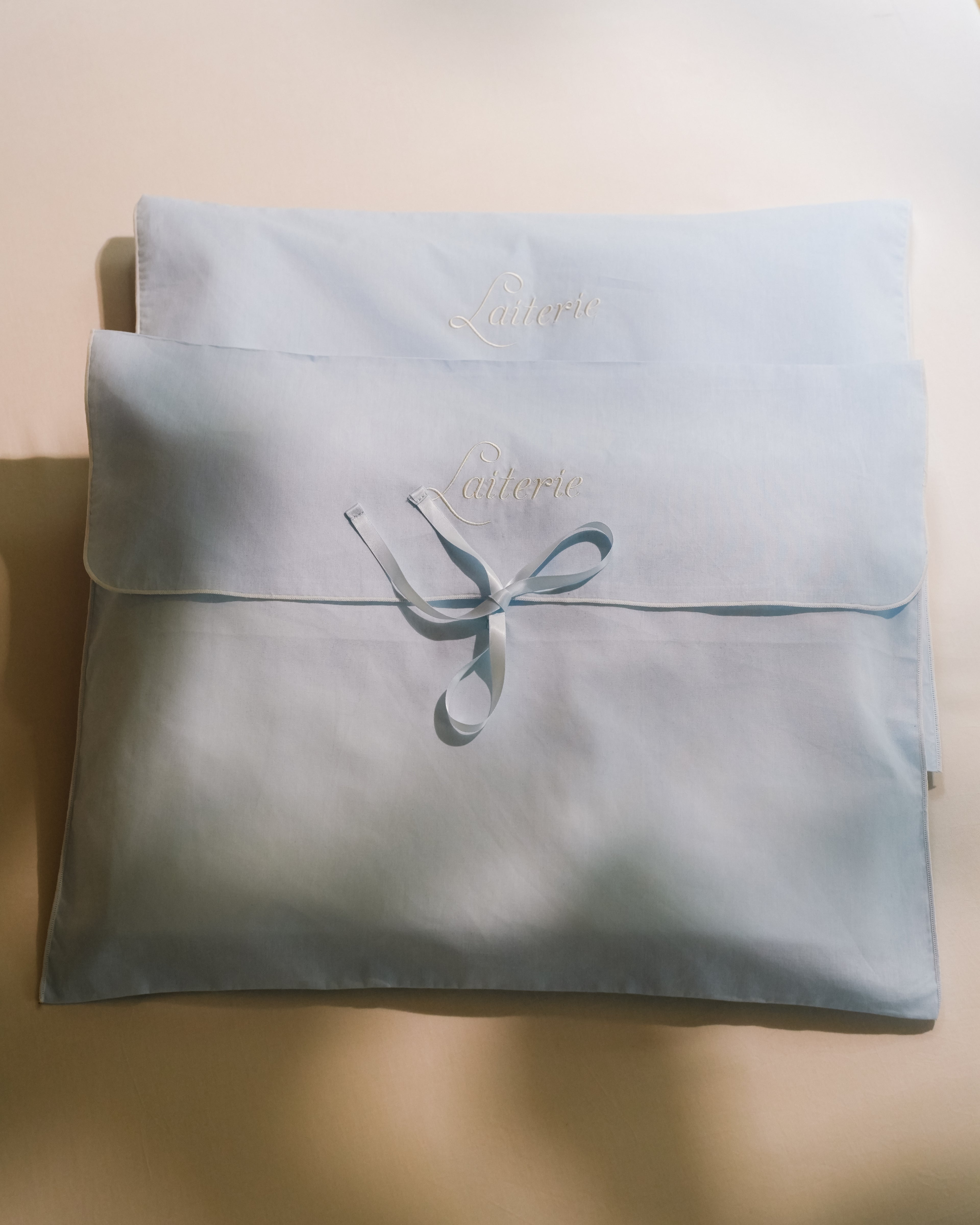 Laiterie cotton muslin keepsake bags in dusty blue with embroidered logo and ribbon tie