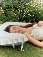 Woman resting on a Chantilly ruffle pillowcase with cotton lace tie detail