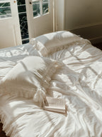 Chantilly ruffle pillowcases styled with romantic ivory bedding in a sunlit bedroom