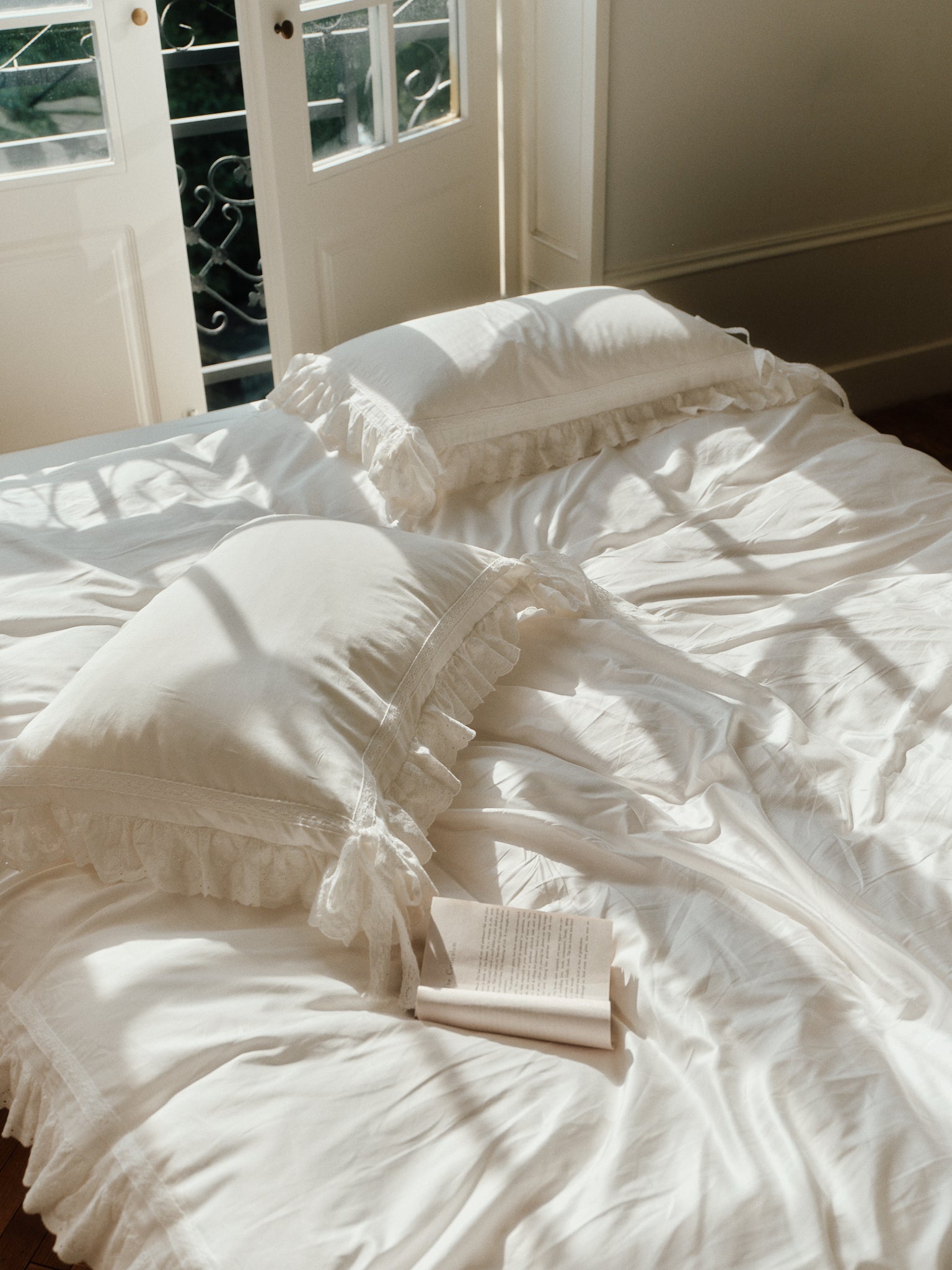 Chantilly ruffle pillowcases styled with romantic ivory bedding in a sunlit bedroom