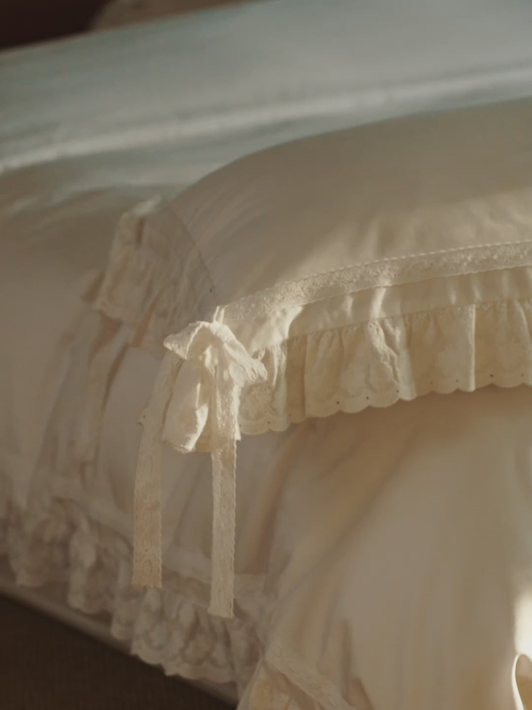 Chantilly ruffle pillowcase with scalloped eyelet detailing styled on an ivory bed