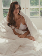Woman wrapped in the Crème layered ruffle duvet cover