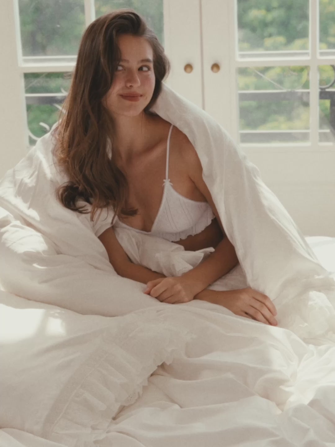 Woman wrapped in the Crème layered ruffle duvet cover